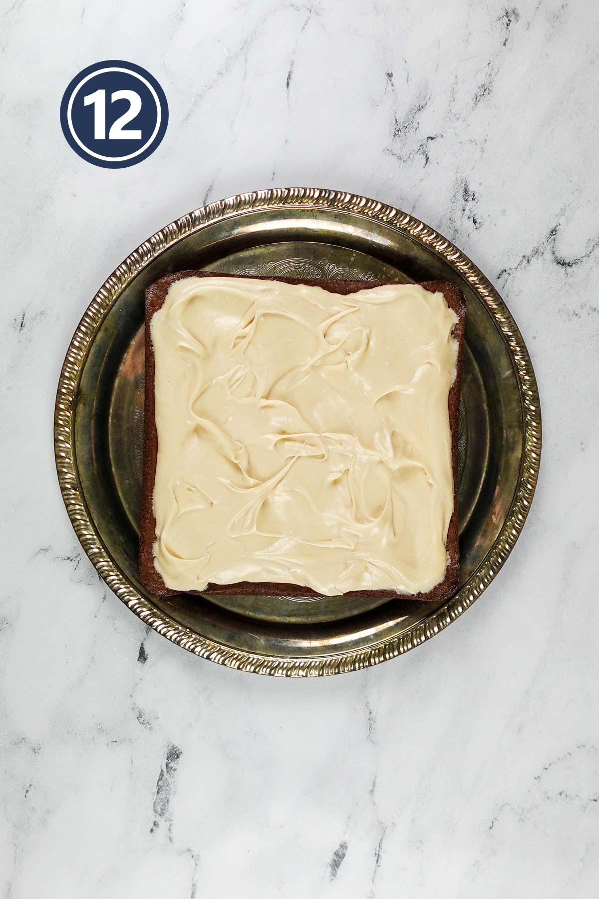 Chocolate brownies with cream cheese frosting in a decorative silver cake plate.