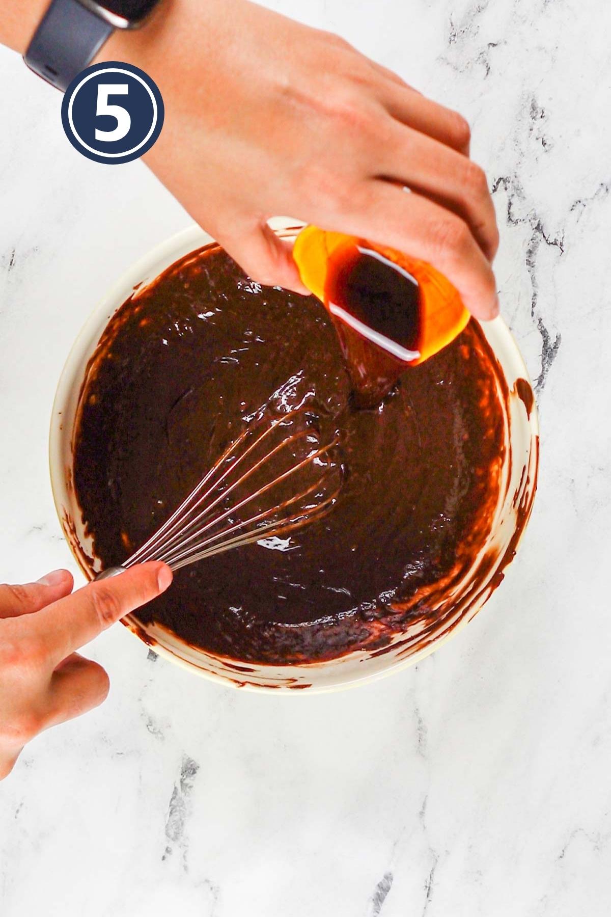 Adding the vanilla extract in the melted chocolate.