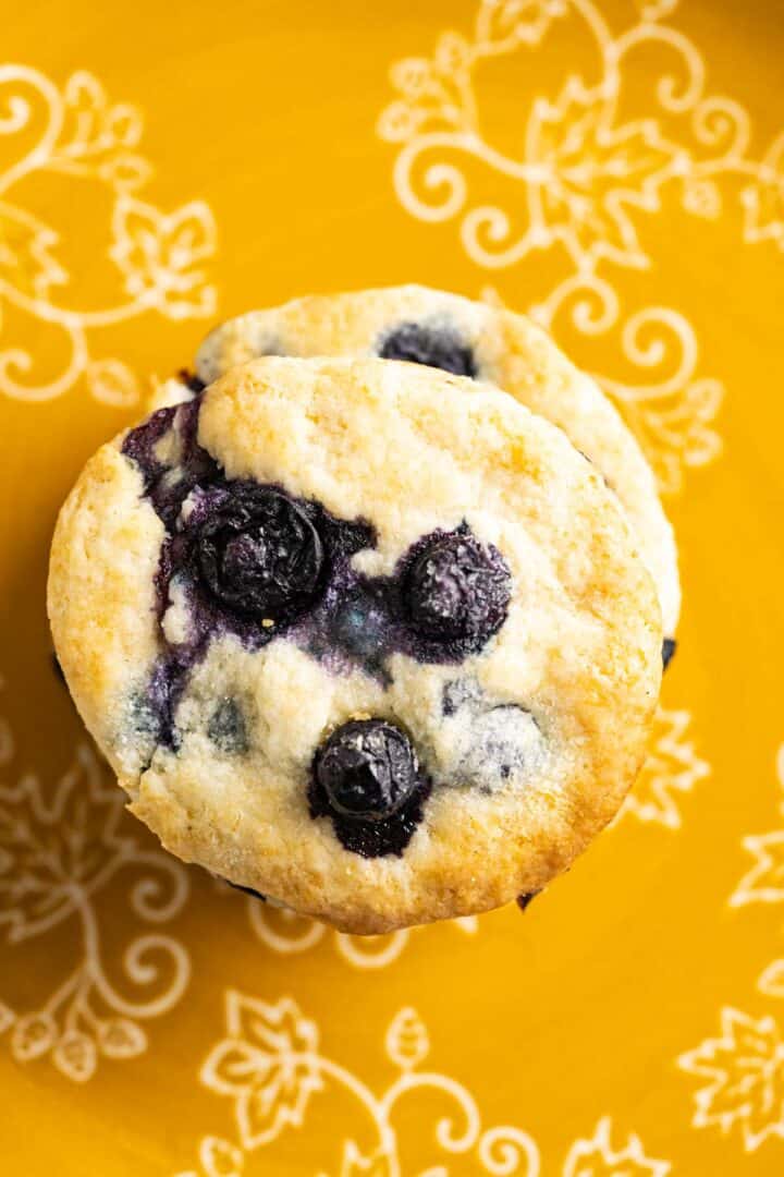 over the head shot of blueberry biscuits sitting in a yellow and white plate.