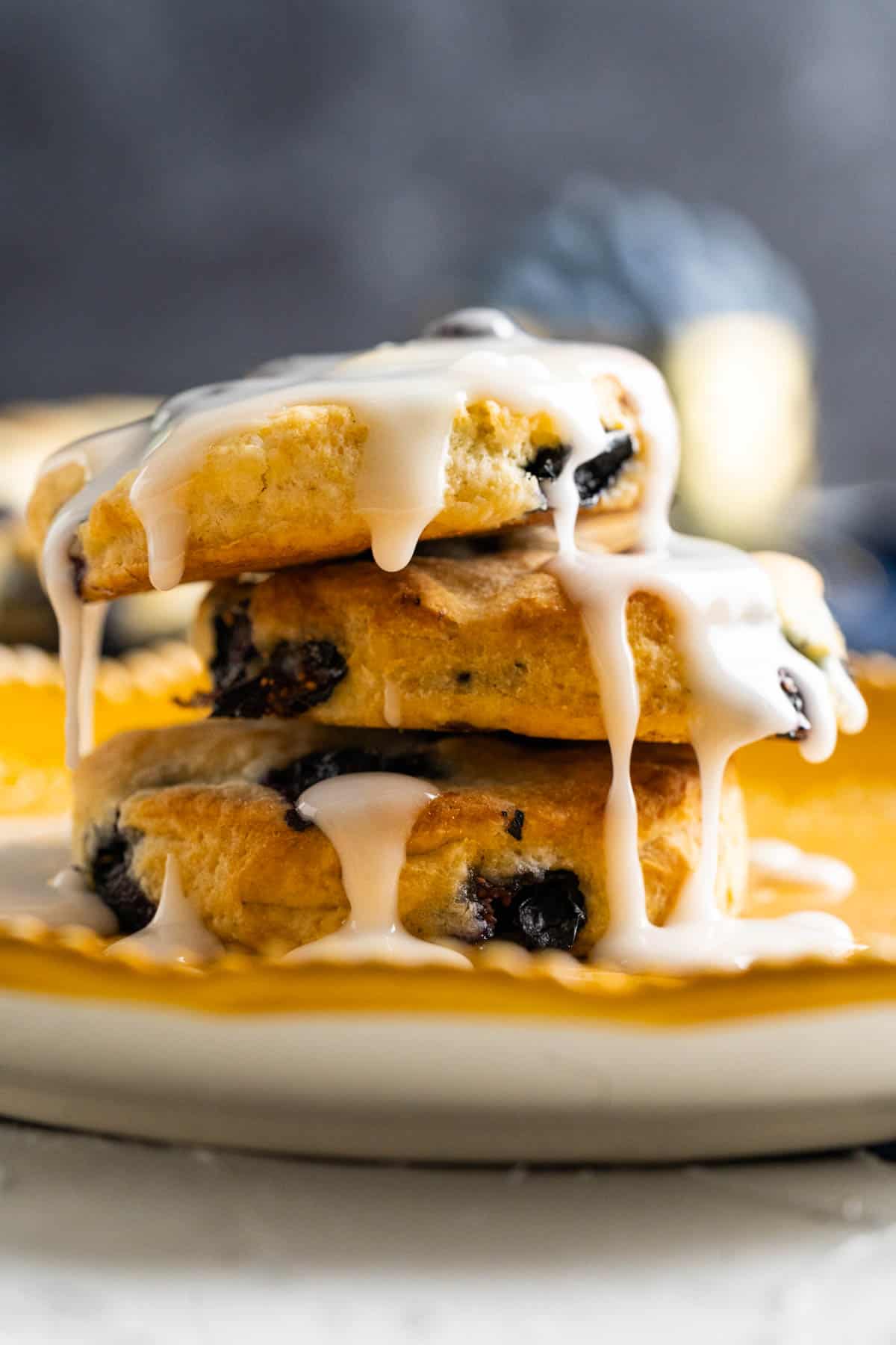 close shot of blueberry biscuits with icing on it placed on each other.