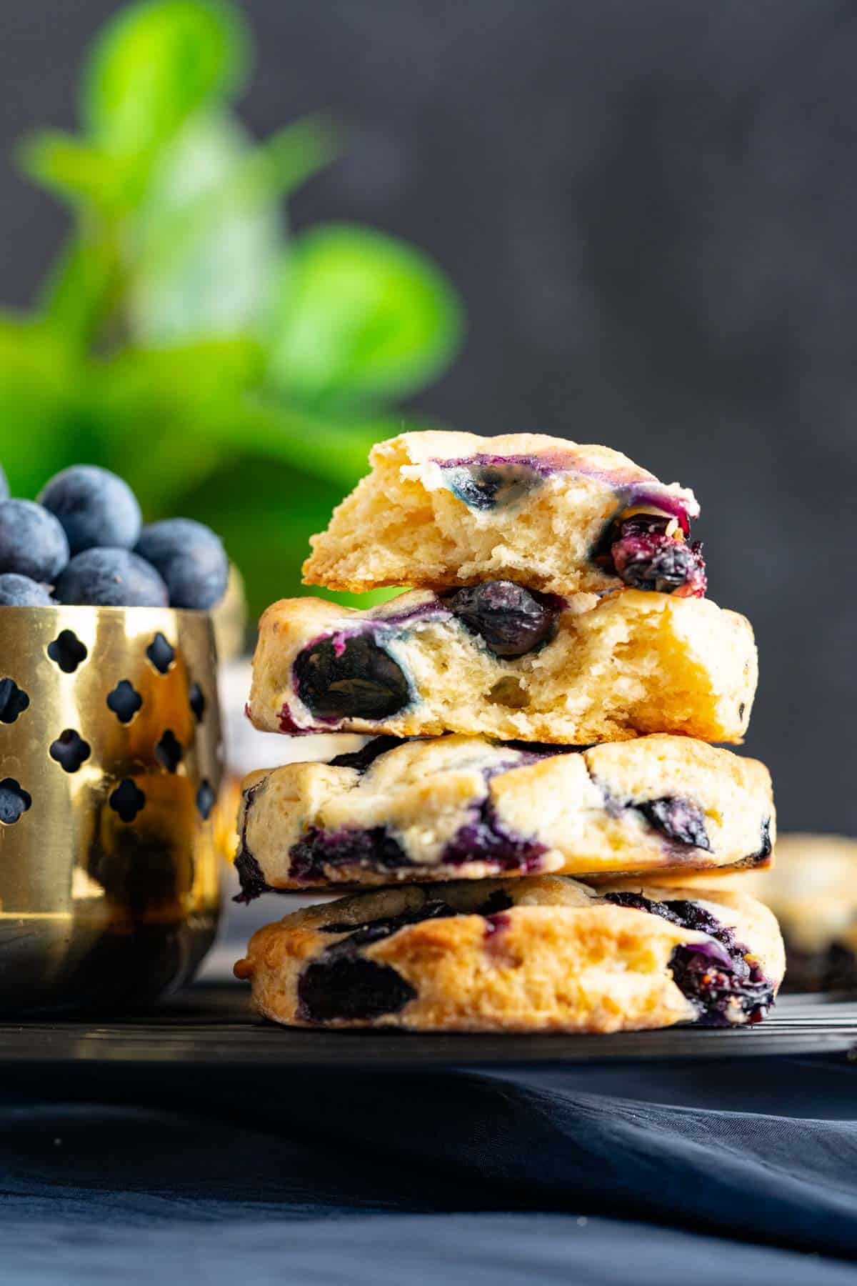 four bojangles blueberry biscuits placed on each other with a golden bowl with blueberries in it.