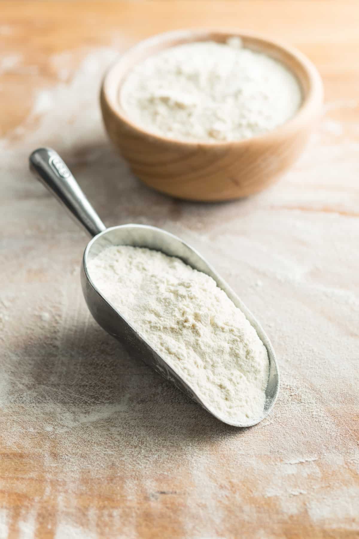 all purpose flour in a big spoon with a bowl behind.