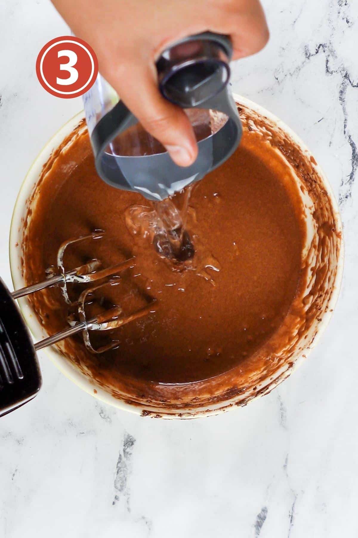 Pouring water over the cake batter in a medium bowl.