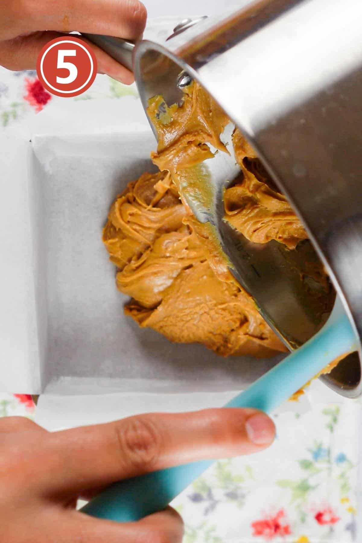 pouring the peanut butter fudge in the 8'' baking pan with parchment paper.