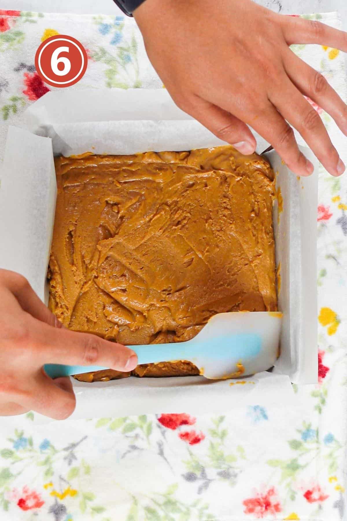 evening the peanut butter fudge with spatula in the baking pan.