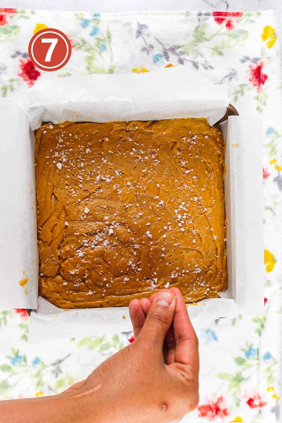 sprinkling sea salt over the peanut butter fudge in the baking pan.