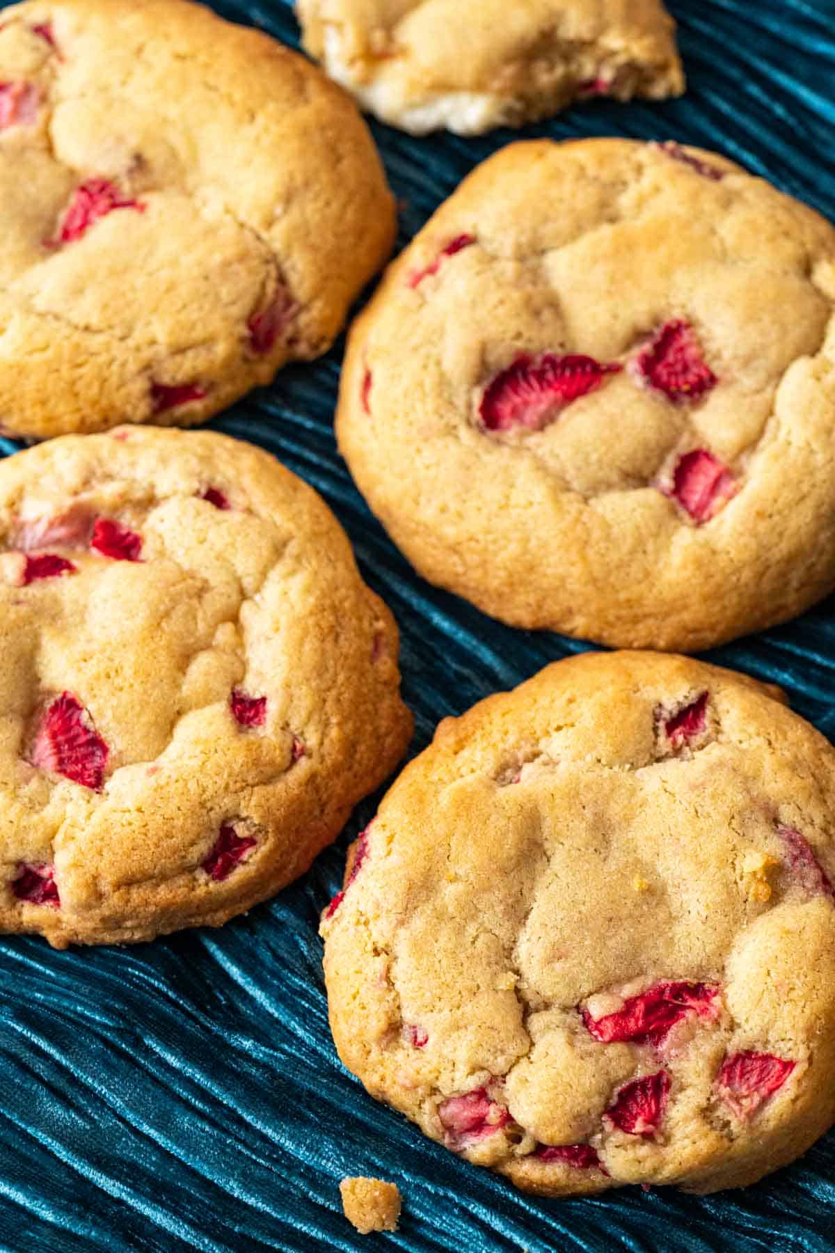 four strawberry cookies sitting on a blue table cloth.