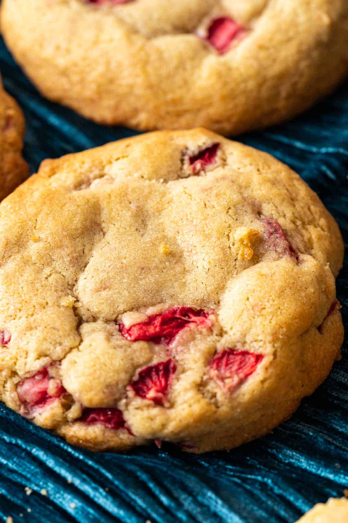 close shot of strawberry cheesecake cookie on a blue table cloth.