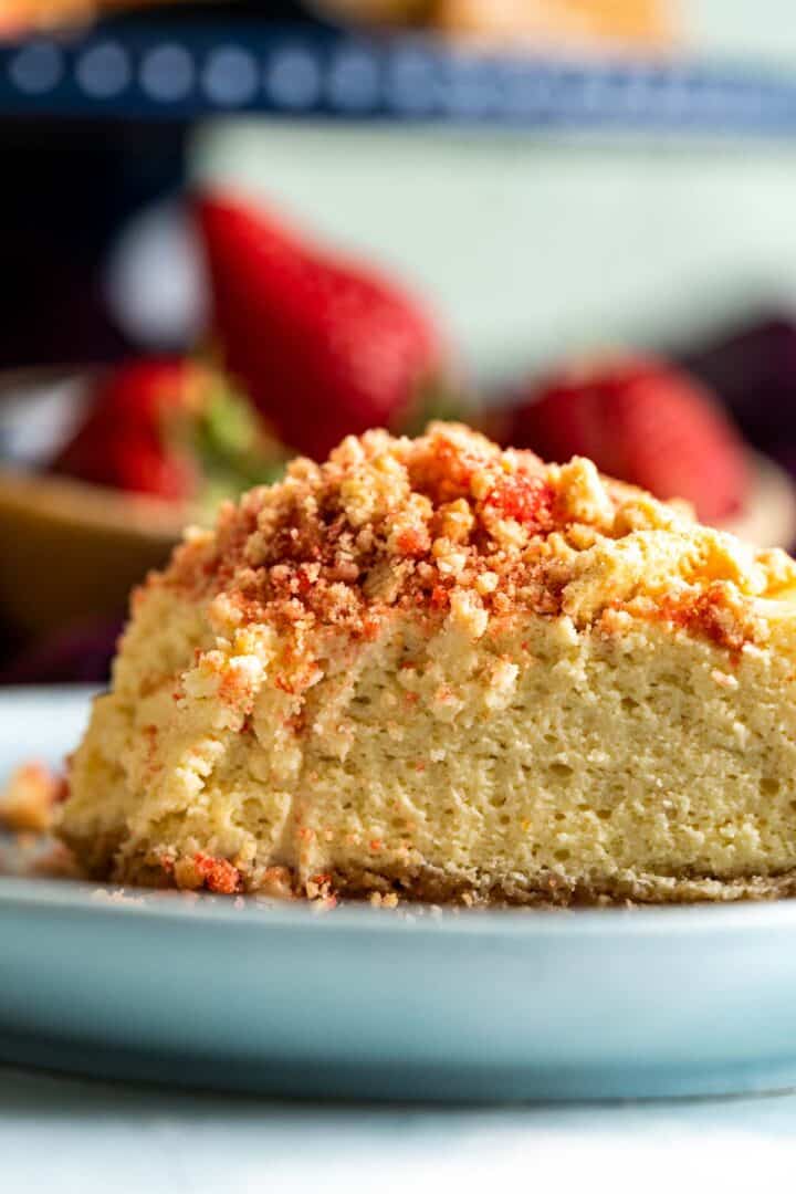 very close shot showing the texture of the cheesecake with a top of strawberry crunch on it.