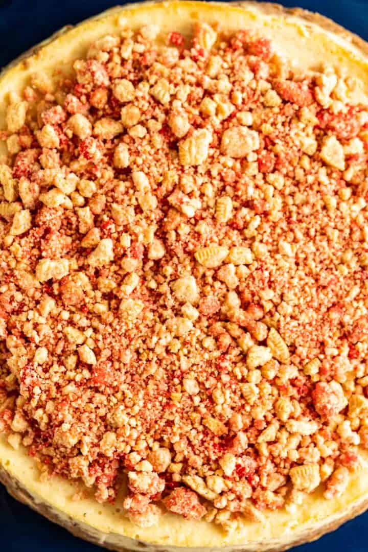 overhead close shot of strawberry crunch sprinkled over the cheesecake.