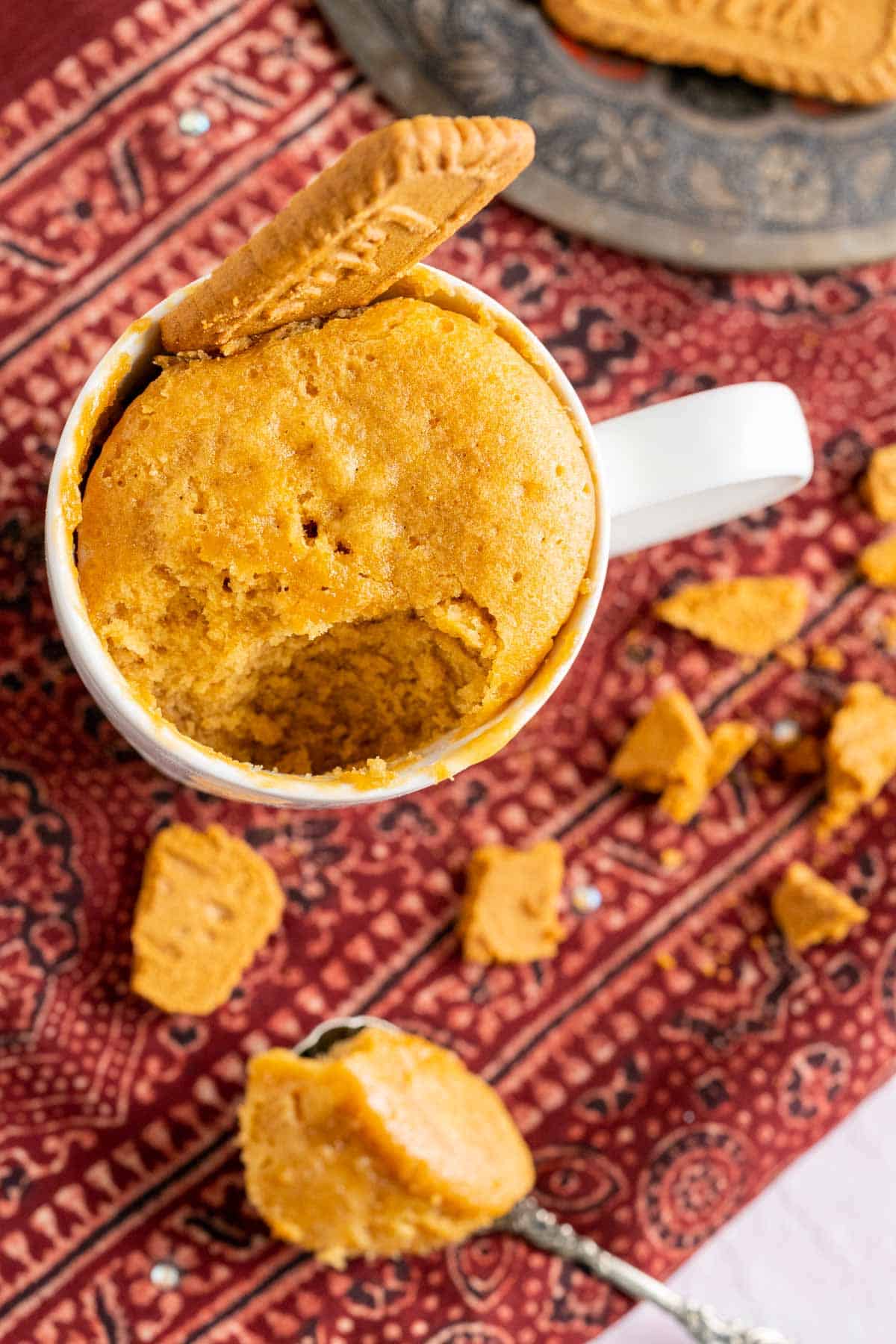 Biscoff mug cake in a white mug with a biscoff cookie inserted to the cake.