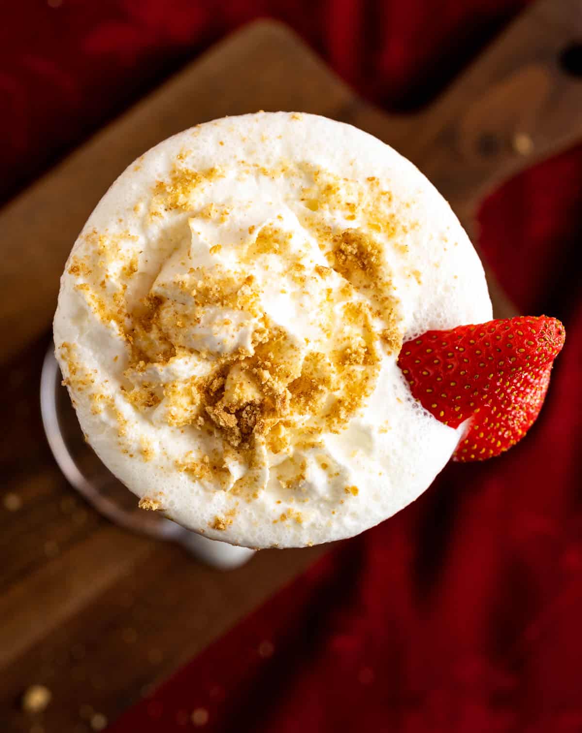 Dollop of whipped cream over Cheesecake Milkshake glass with crushed nuts sprinkled on it. 