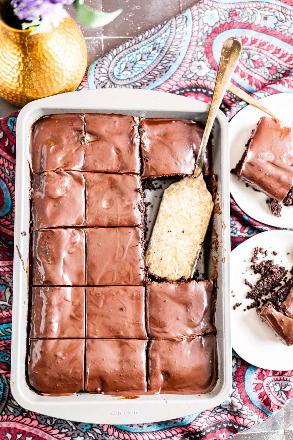 Chocolate cake sitting in a sheet pan with a golden spoon.