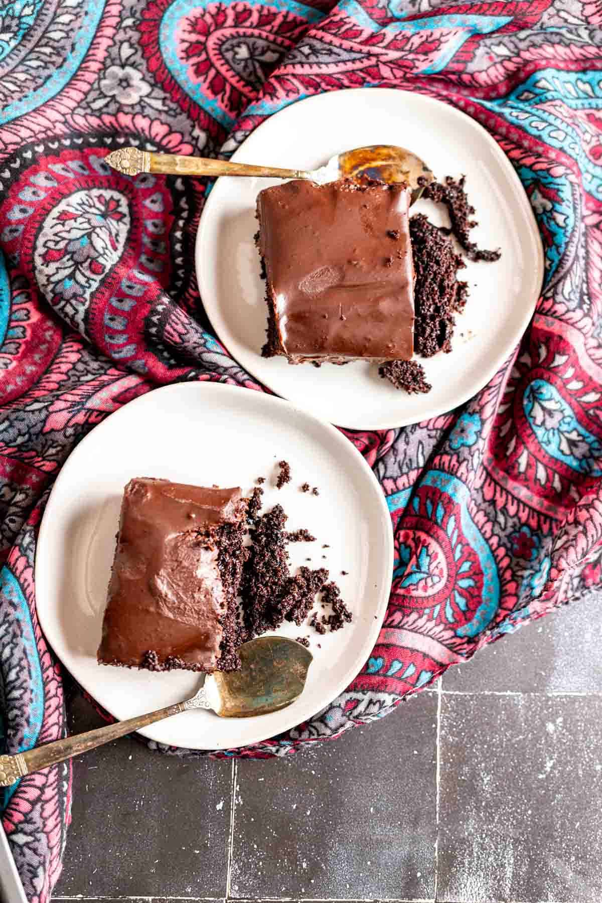 Cake pieces of chocolate cake in small white plates with antique spoons.