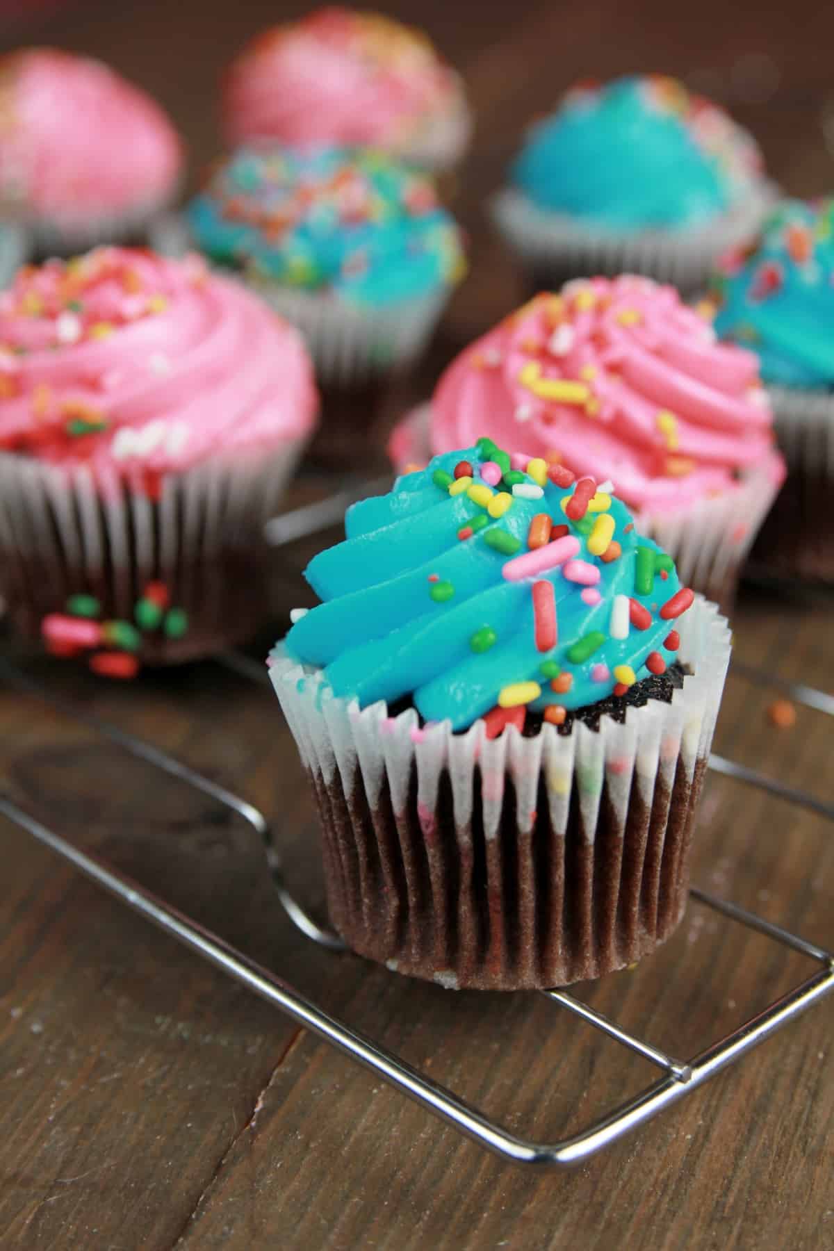 line of frosted cupcakes sitting on the wire rack.