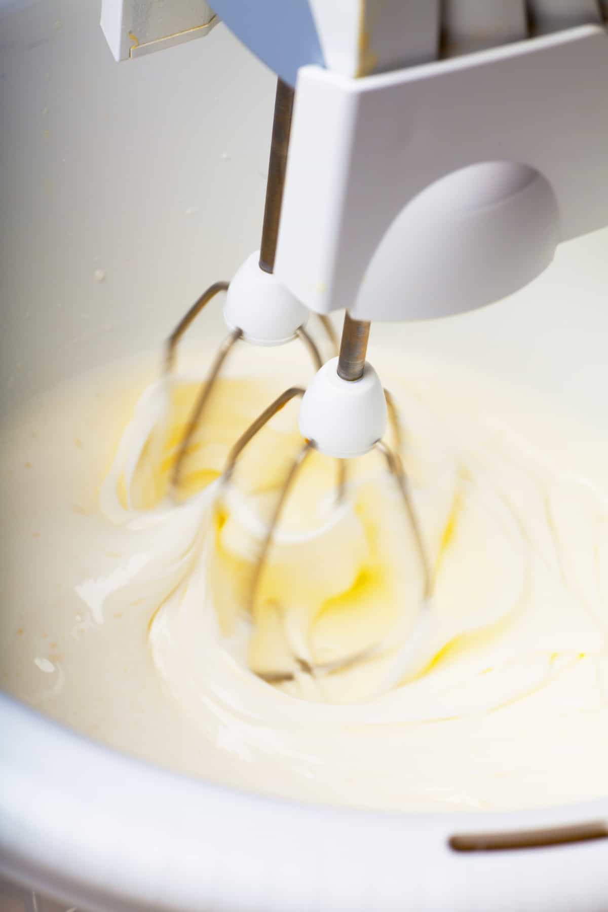 beating the butter, sugar and eggs in a white bowl.