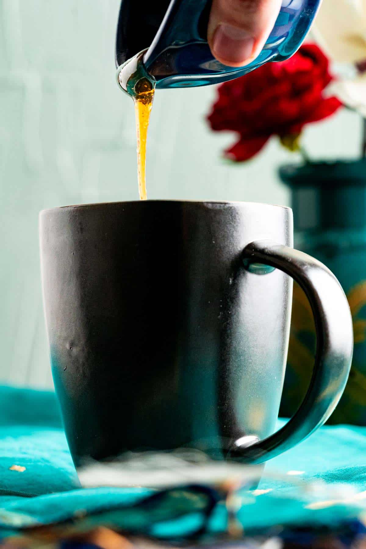 Pouring honey on the cake in blue table cloth.