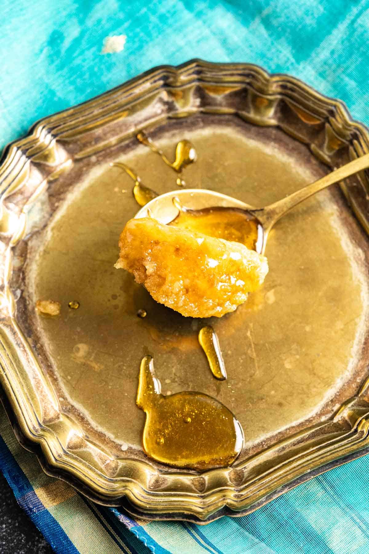 A bit of a mug cake in a golden spoon on a small antique golden plate.