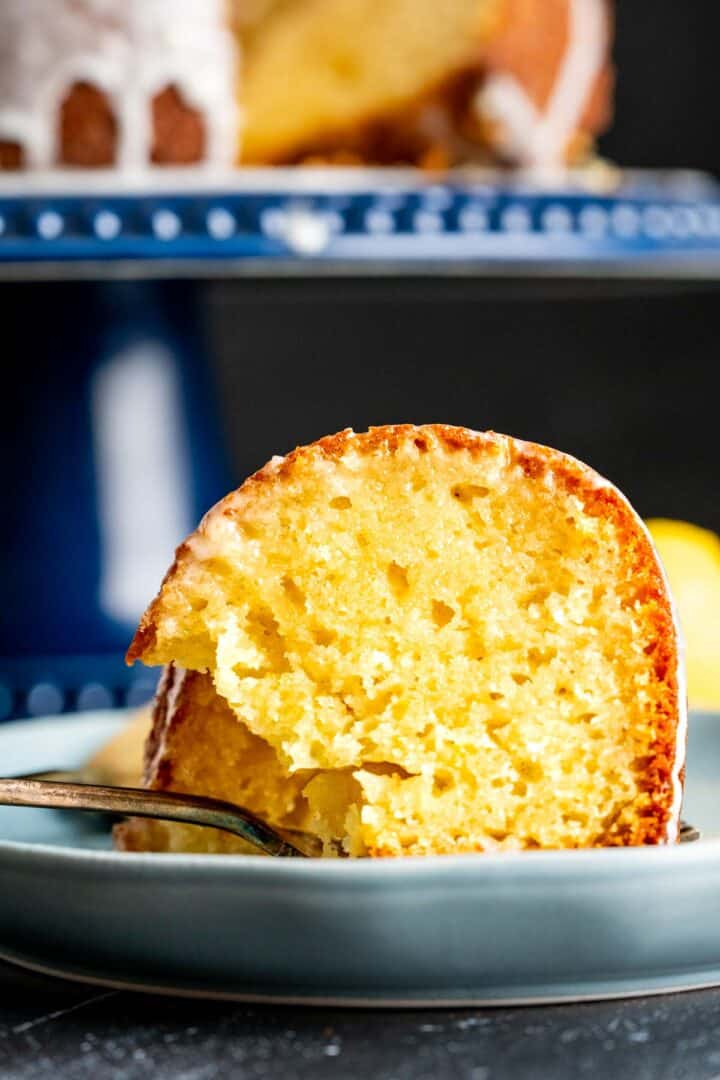 one individual slice of the lemon yogurt cake placed on a blue plate on the black table.