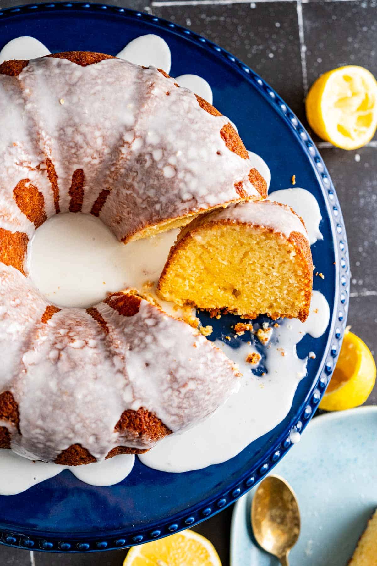 overhead shot of the lemon yogurt cake with a cut slice on the side placed on the black table.