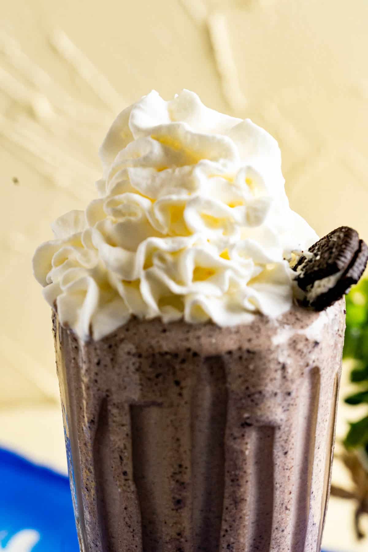 Serving glass with Oreo banana milkshake with a dollop of whipped cream on the top.