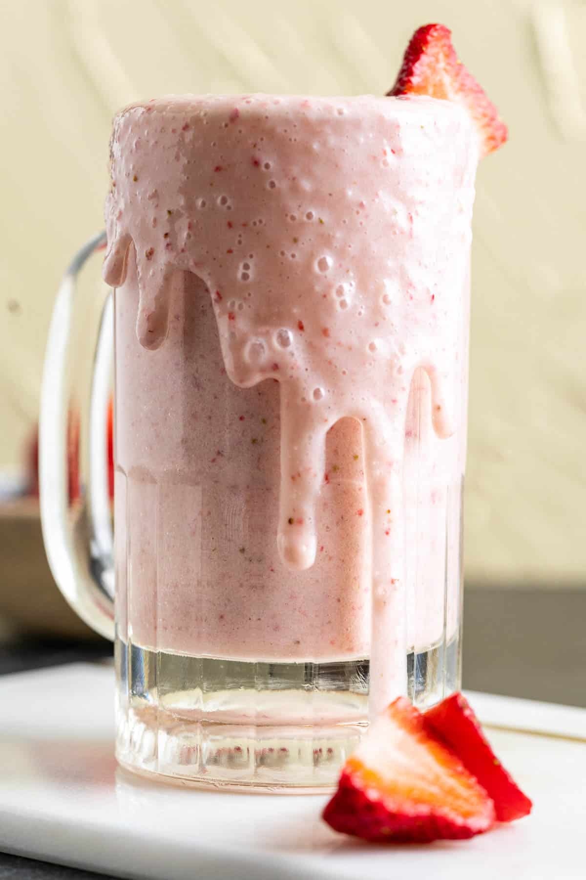 Strawberry banana milkshake in a glass with a piece of strawberry stick in the glass. 