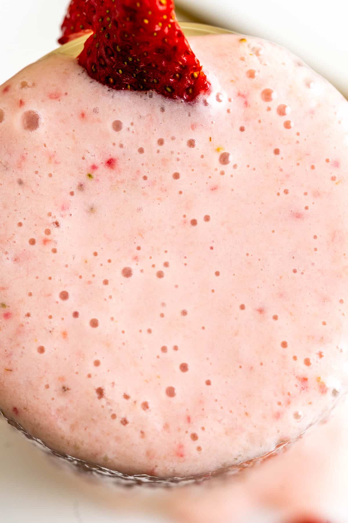 Banana milkshake with strawberry in a glass showing the texture.