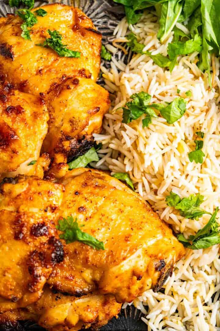 chicken pieces sitting with boiled rice on a tray.