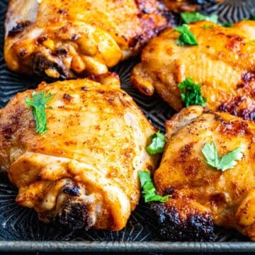 closeup of chicken thighs on a silver tray.