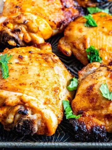 closeup of chicken thighs on a silver tray.