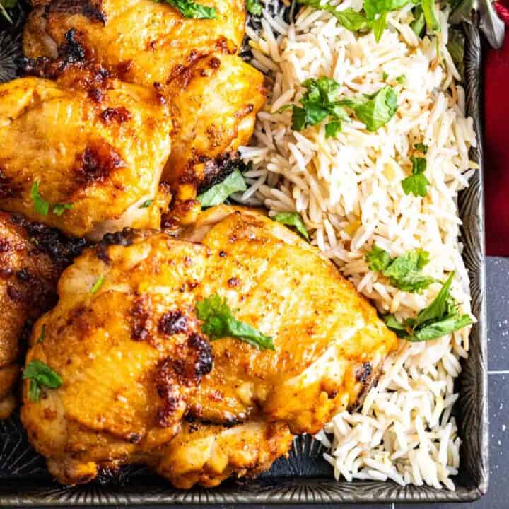 one piece of chicken thighs shown closely with rice on the side.