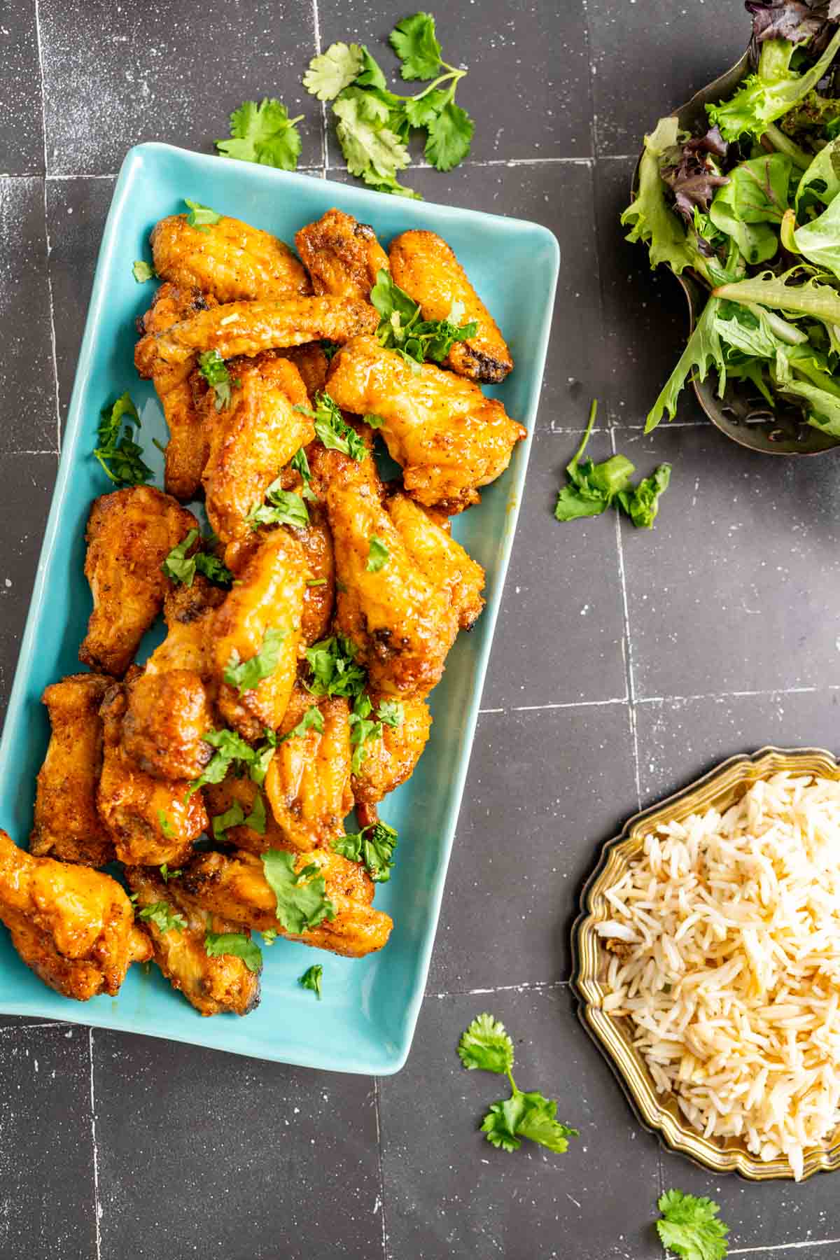 Honey lemon pepper wings in a blue plate with rice in an antique plate in the side.