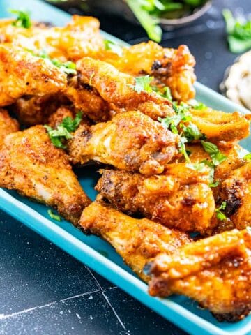 honey lemon pepper wings in a rectangular plate with salad and rice on the side.