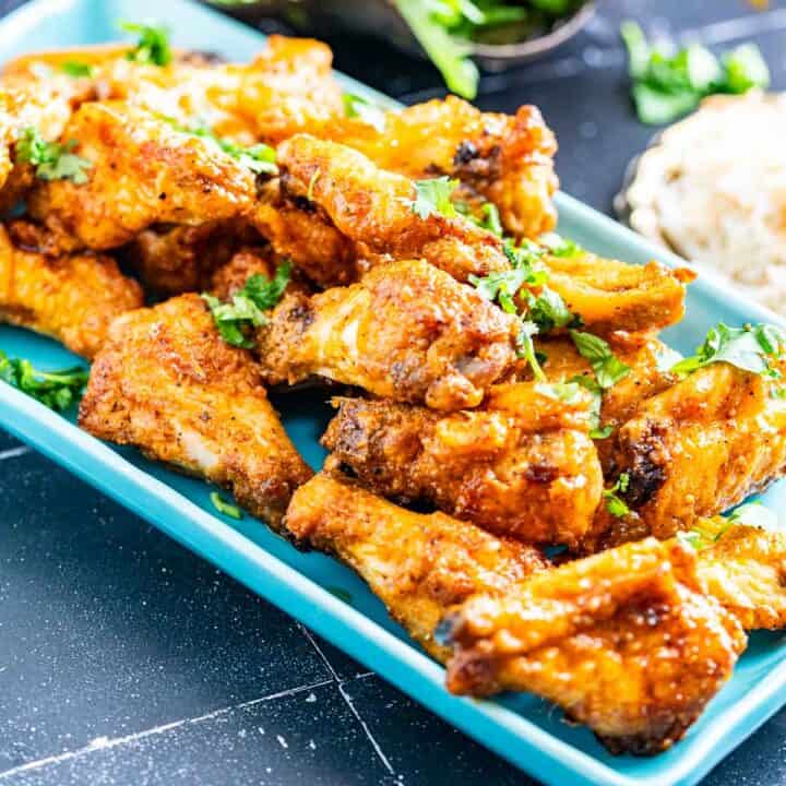 honey lemon pepper wings in a rectangular plate with salad and rice on the side.