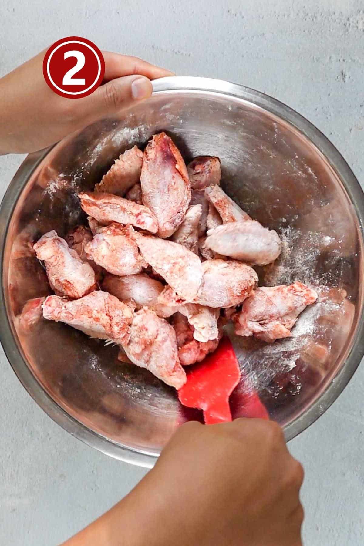 Coating the chicken wings with spices in a large mixing bowl.