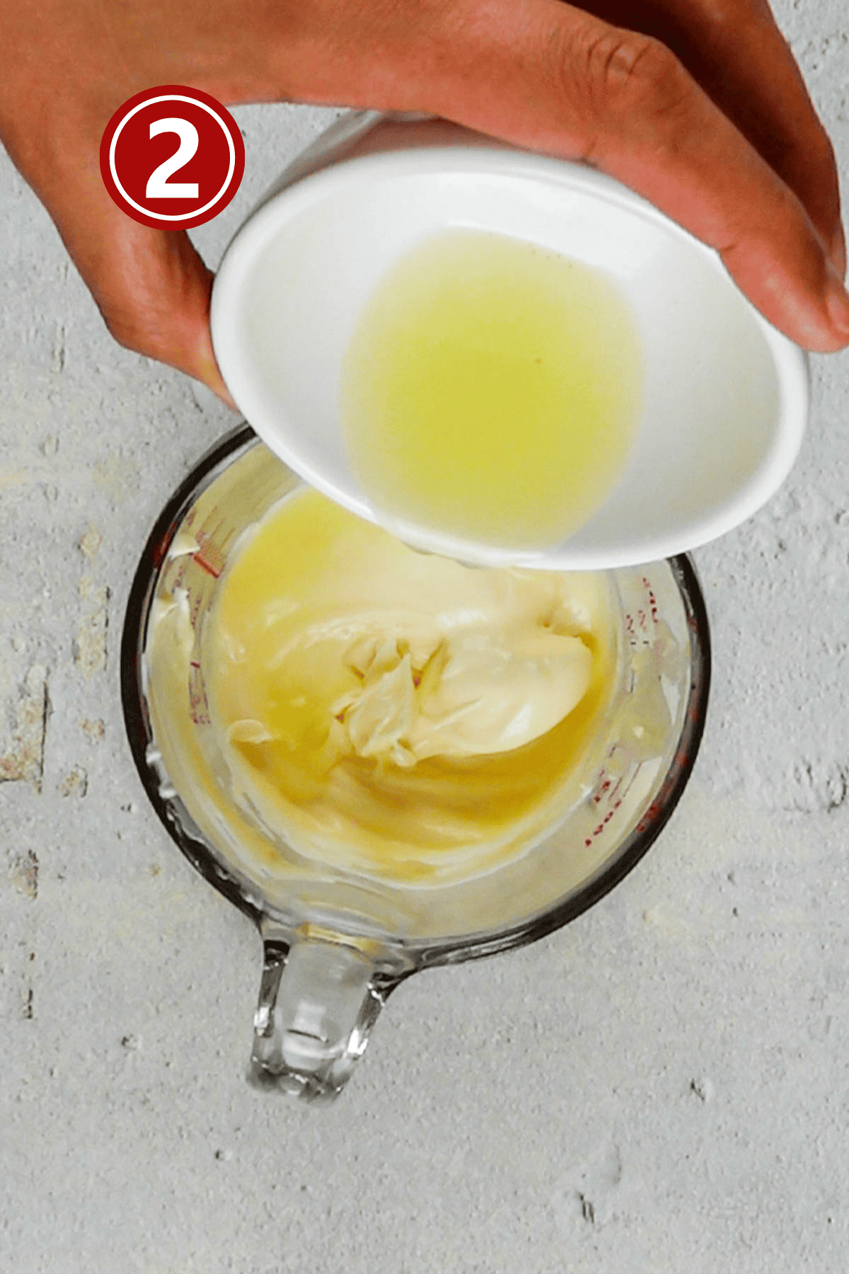 Adding lemon juice to the mayonnaise in the glass.