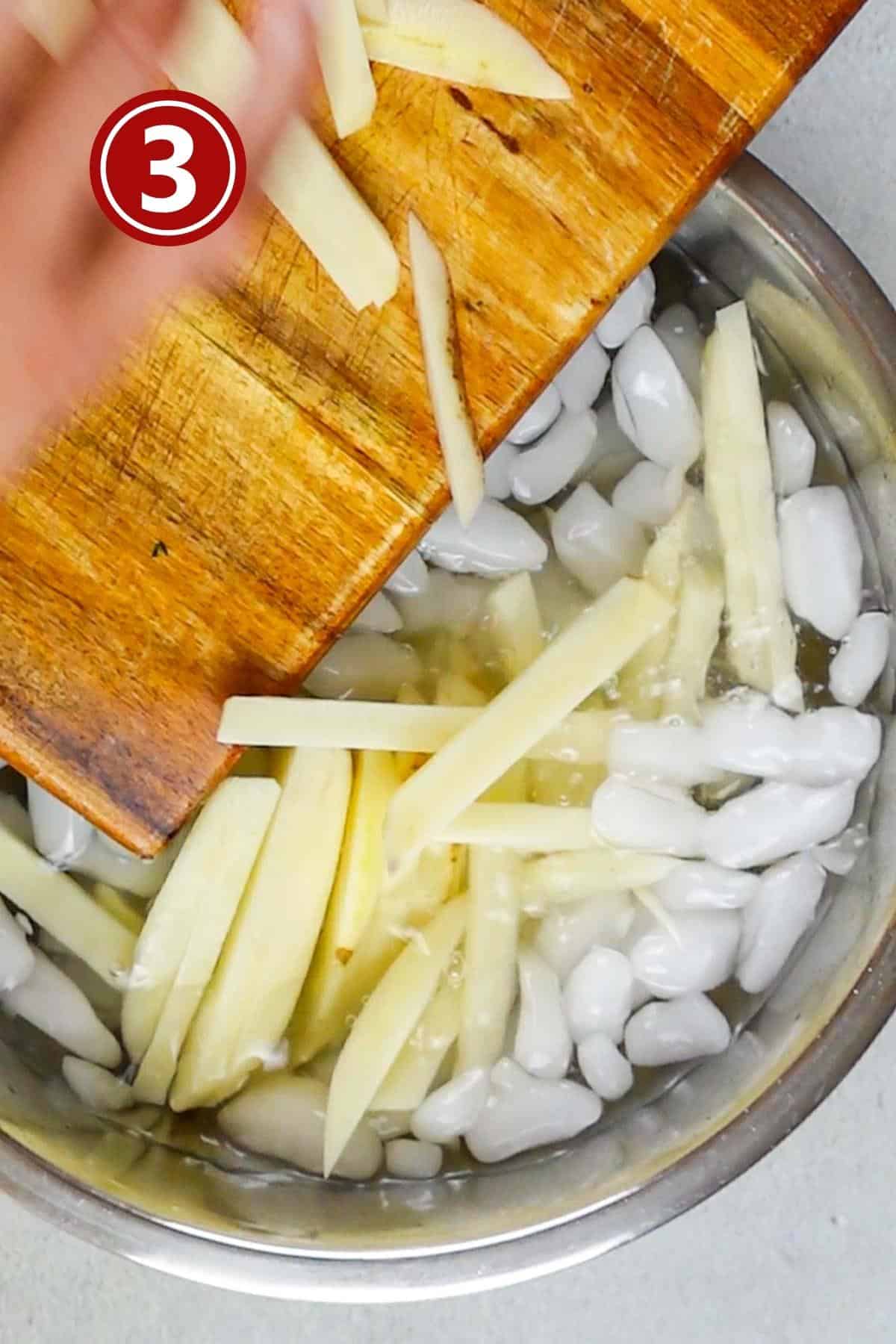 Adding the potato pieces to the cold water in a large steel bowl.