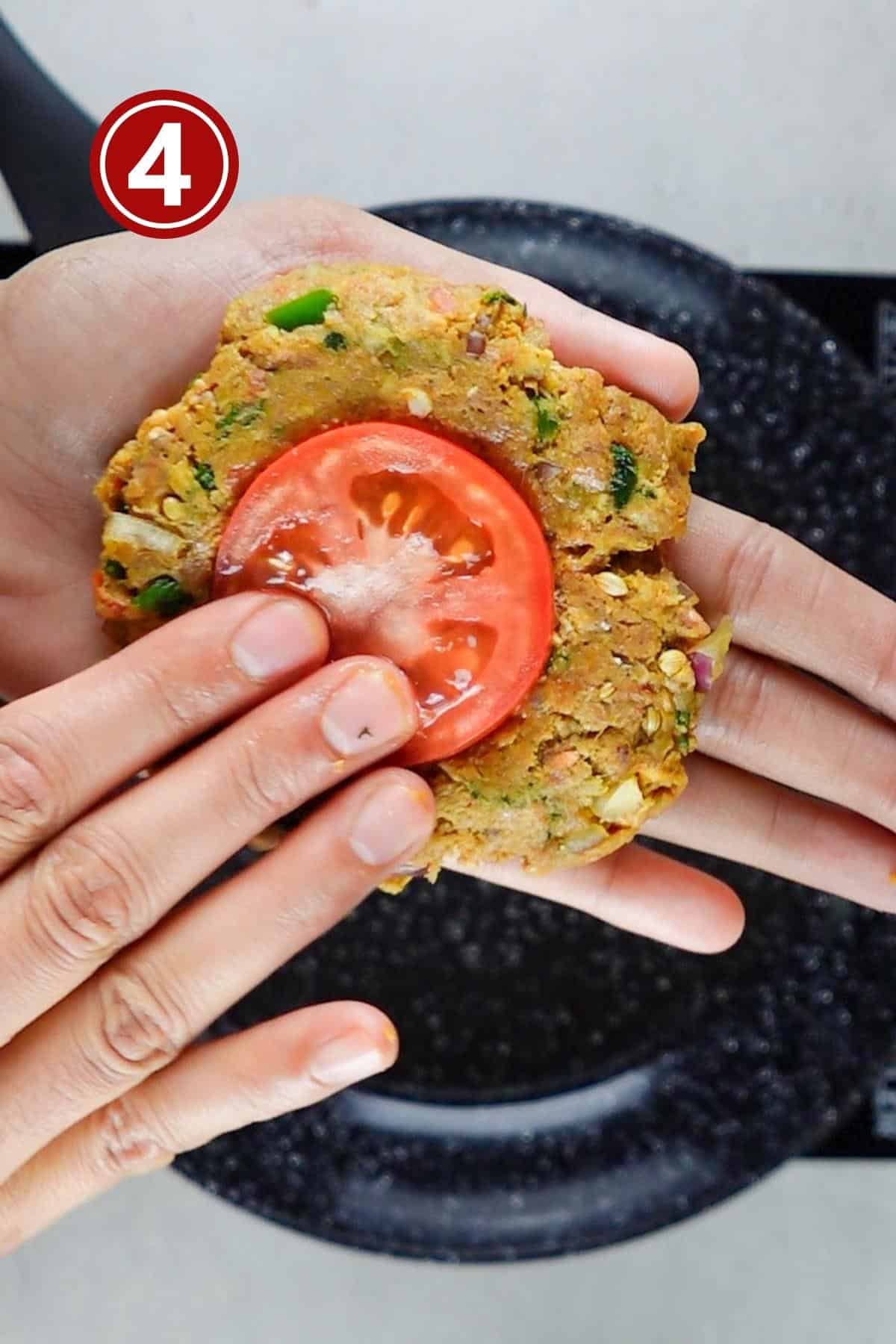 Pressing a tomato slice into the kebab before frying.