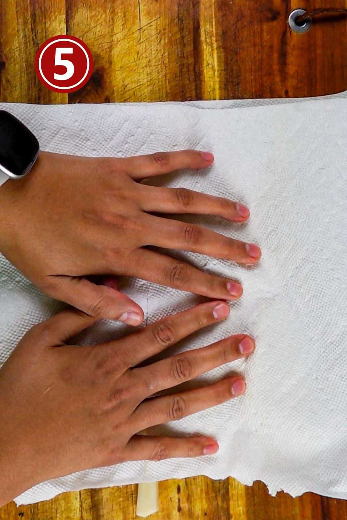 Patting dry the fries using paper towels on a wooden board.