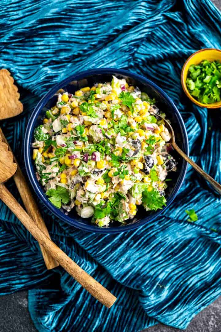 from the top shot of the salad in a blue plate with coriander scattered around on the blue table cloth.