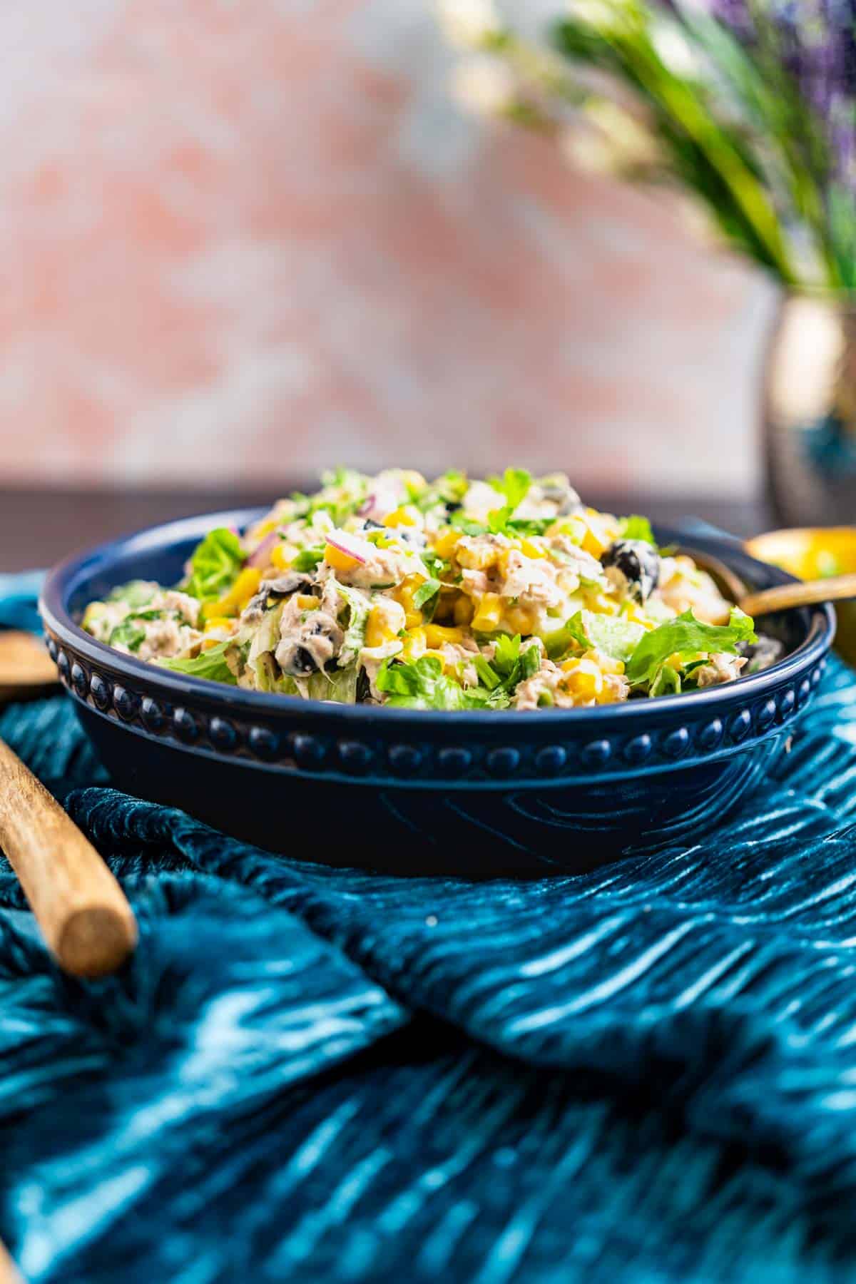 Tuna salad in a blue plate with wooden spoons around.