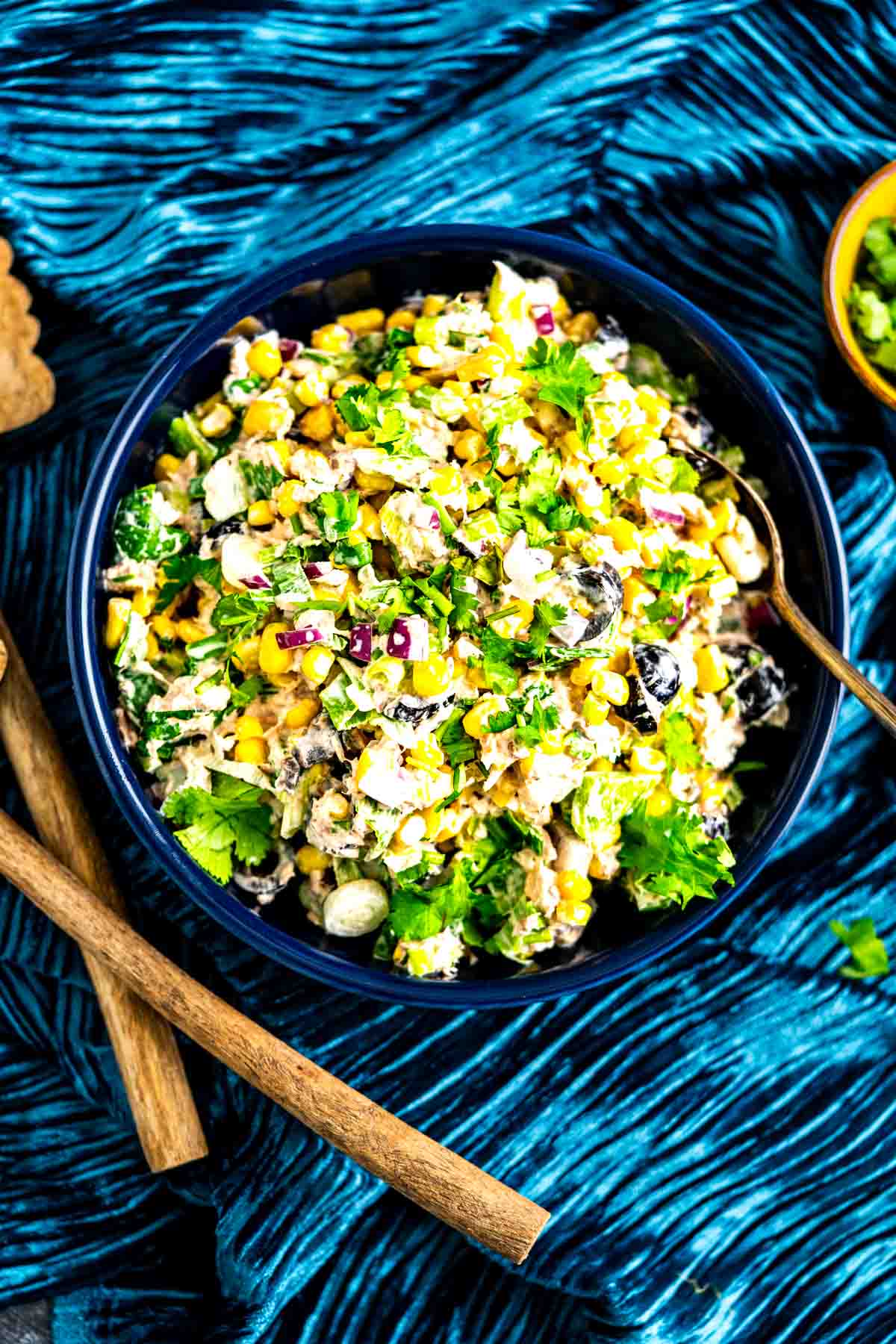 Salad with tuna in a big bowl placed over a blue table cloth.