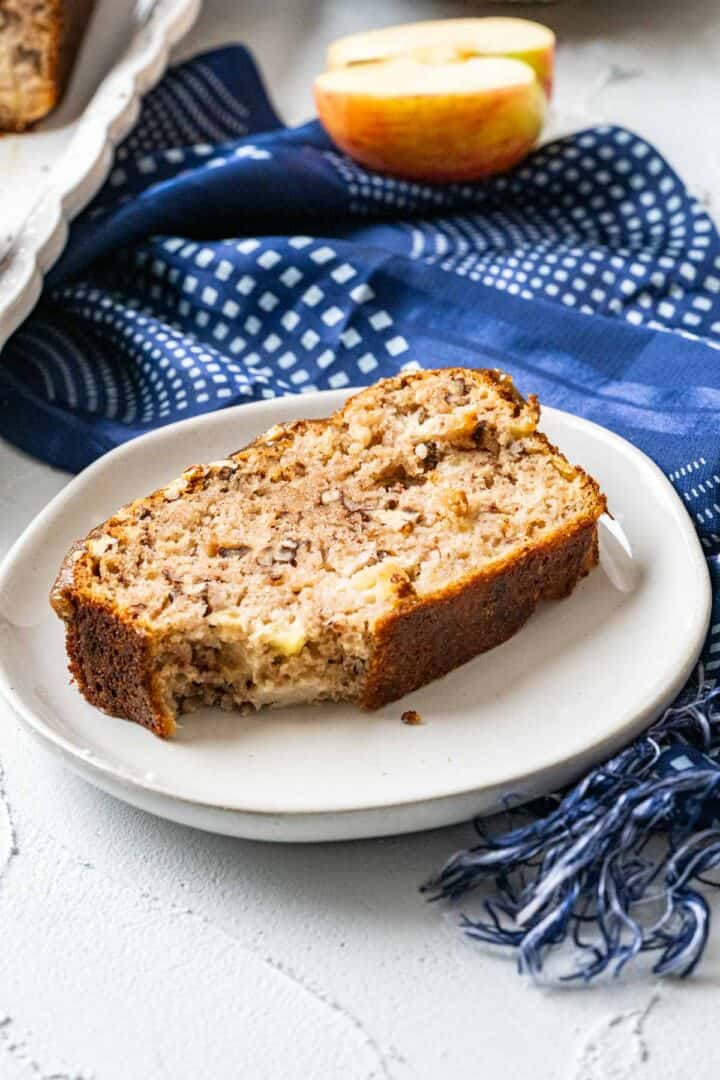 one piece of apple bread with apple in the backdrop.