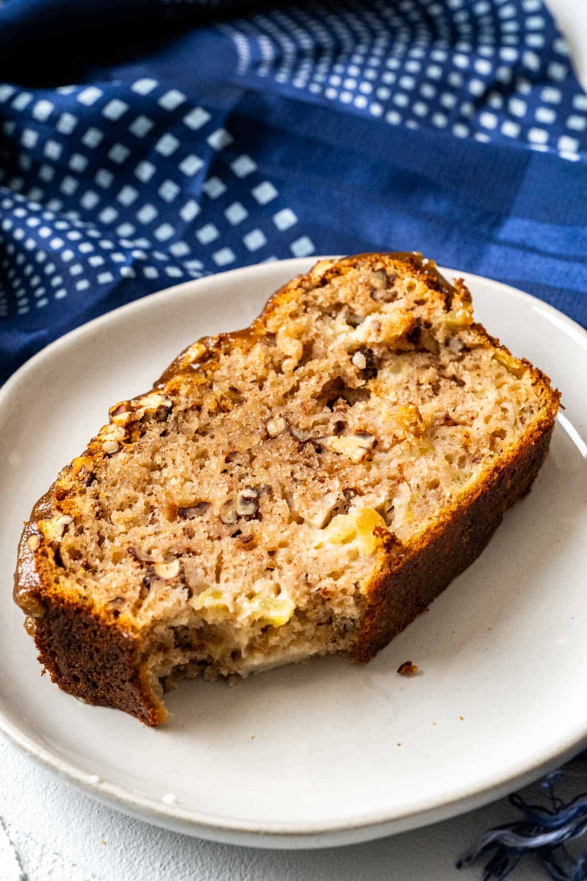 A slice of apple bread showing the pecans and apple pieces.