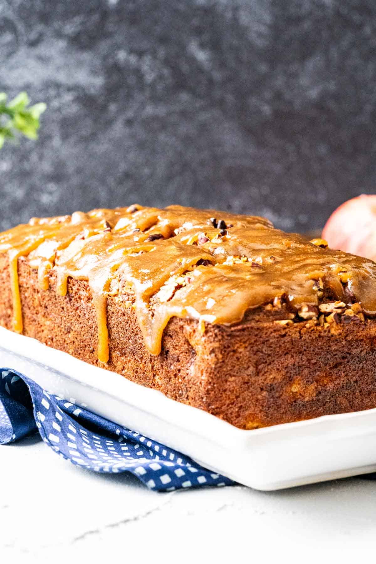 Apple praline bread in a white plate on a blue and white table cloth.