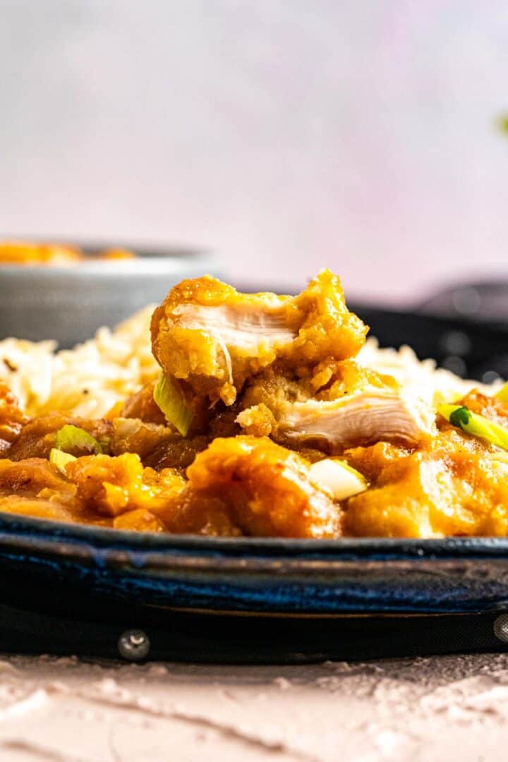 chicken piece half cut and showing texture sitting on a gravy in a plate.