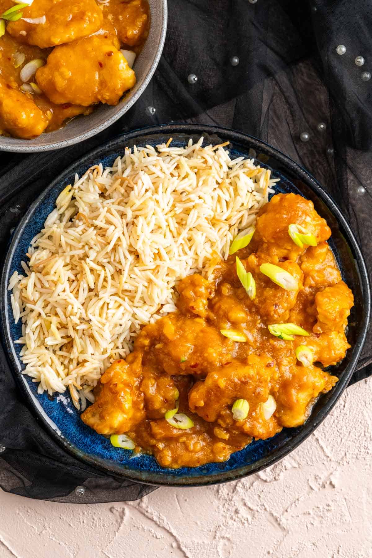 Orange Chicken Cheesecake Factory served with white rice in a dark blue plate.