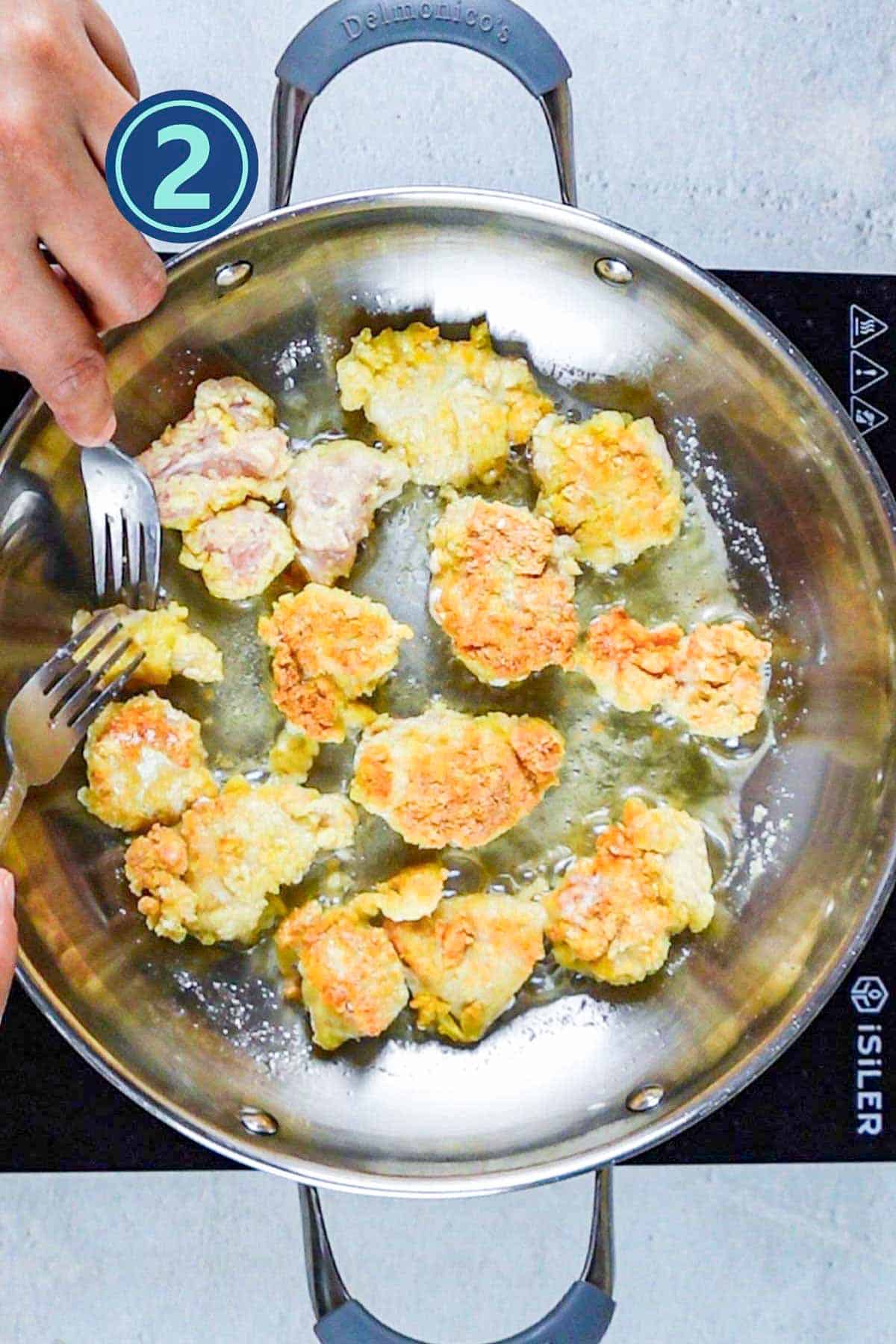 Fried chicken pieces in a frying pan.