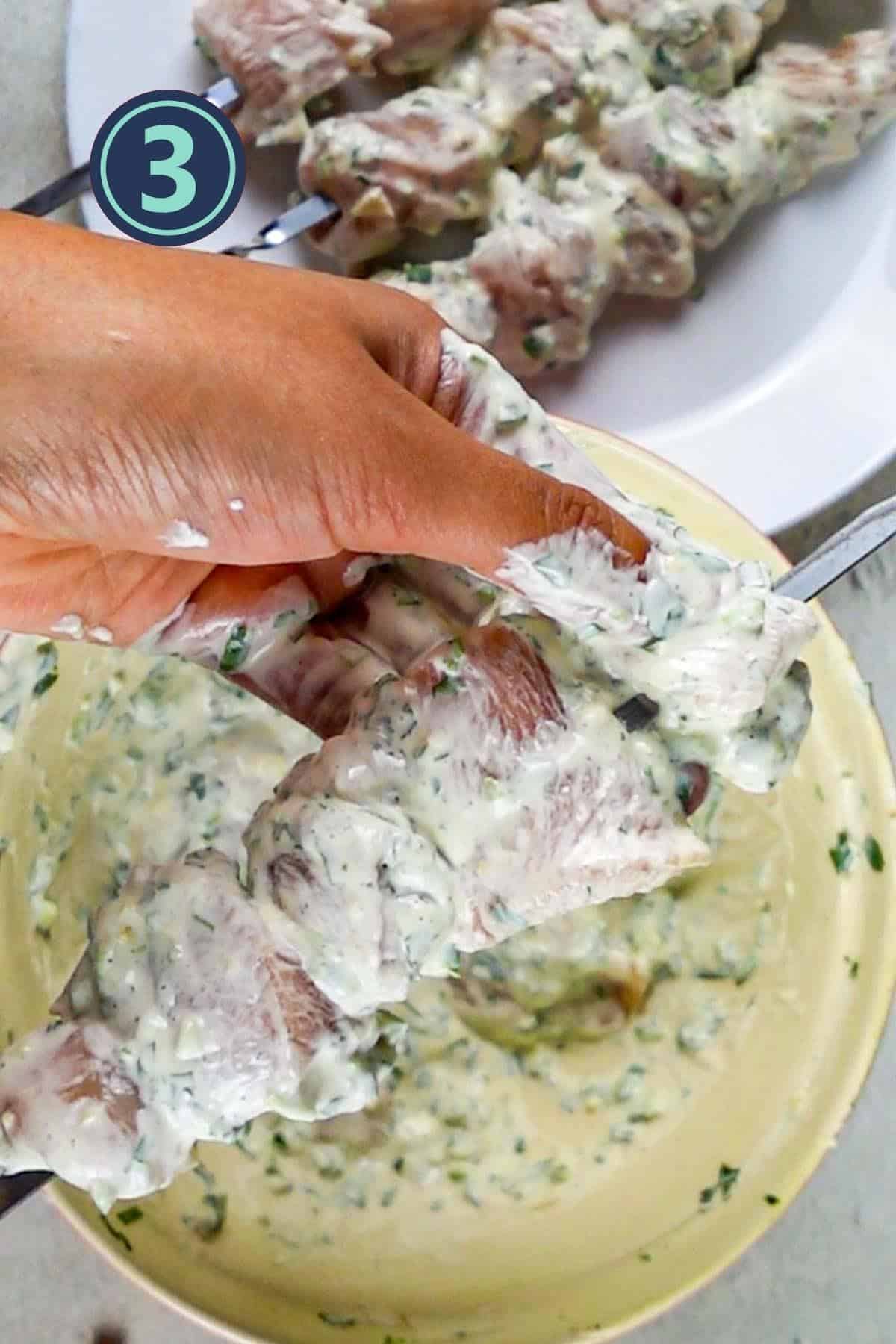 Threading the chicken boti into the steel skewer.