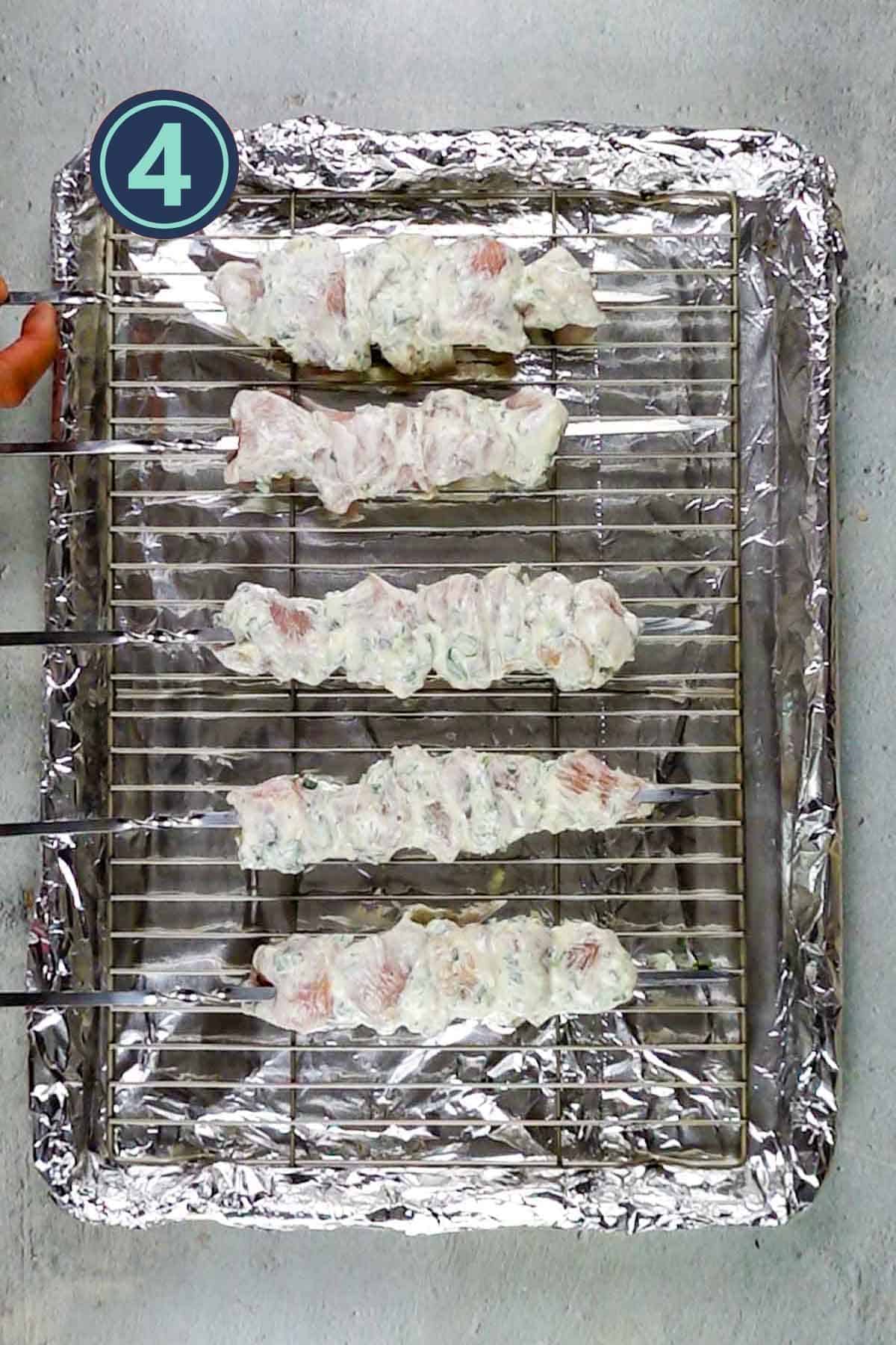 Placing chicken skewers on the baking tray with foil beneath covering the baking tray.